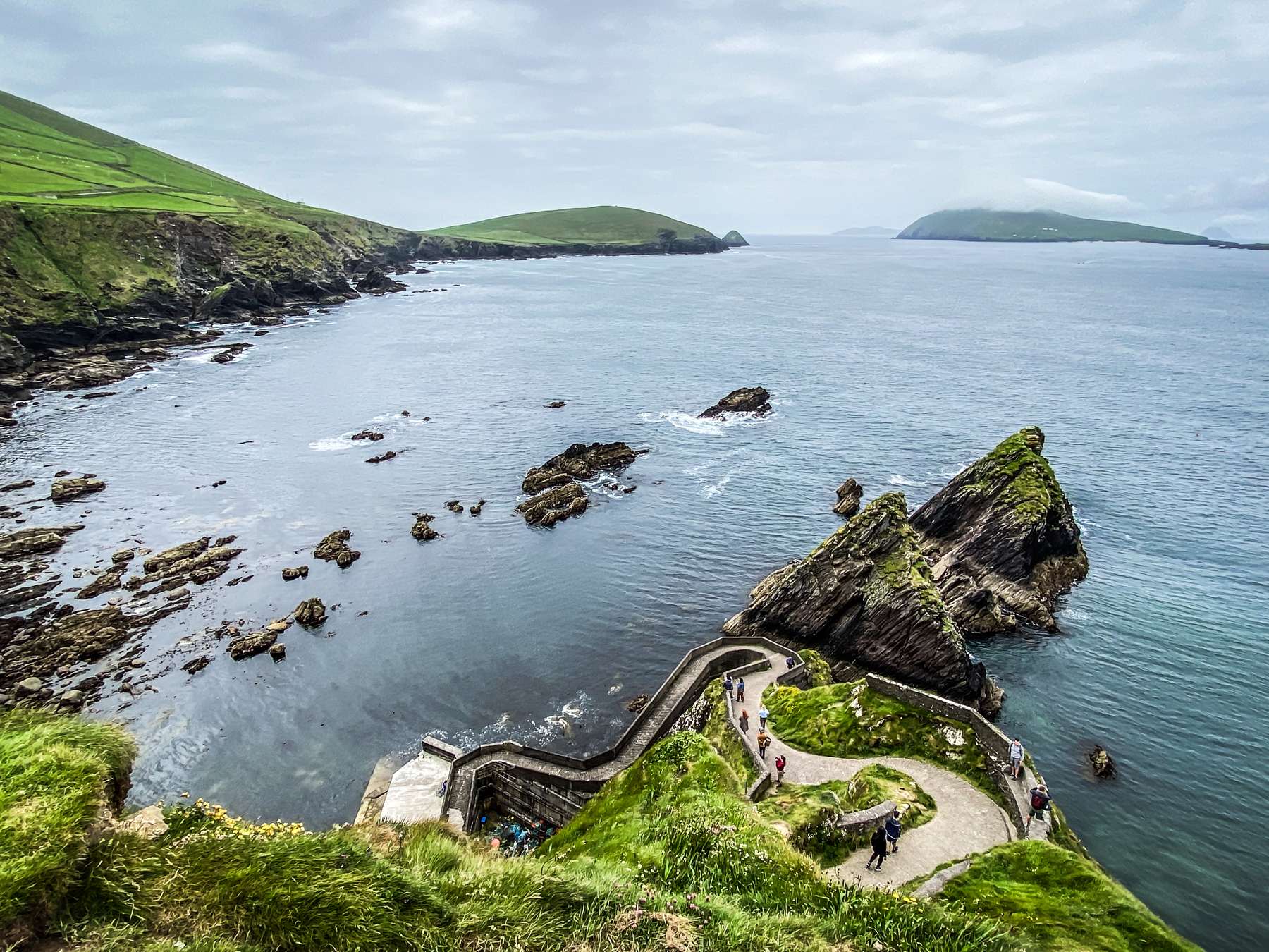 The zig-zag walkway of Dún Chaoin Pier winding down the cliff to the water, with the Blasket Islands across the sound